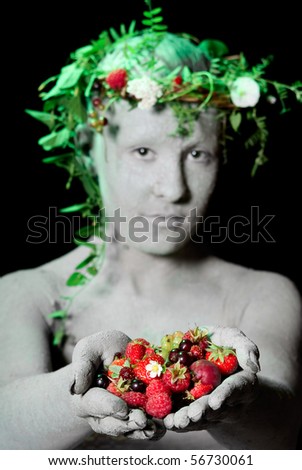 Mother earth holding berries in her hands. Black background. Studio shot.