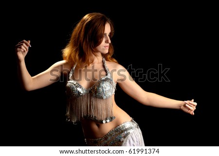 Young sexy woman dancing belly dance. Black background. Studio shot.