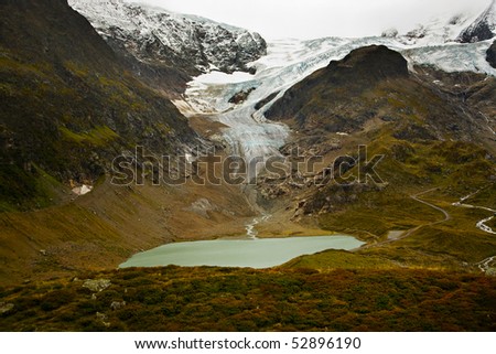 A glacier comes over the top of a mountain and a stream coming off of it runs into a small lake near the Suestenpass in the Swiss alps