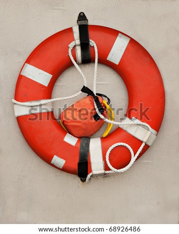 An orange life-preserver, or life-saver, ring hangs on the wall of a boat.