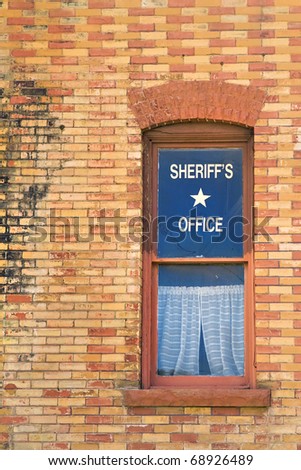 A window in an old red and yellow brick building in the American West with a star and a sign reading 