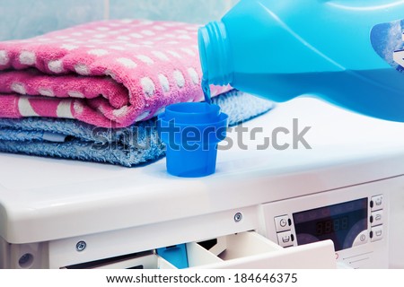 The washing machine which costs in a bathroom. The woman pours a washing-up liquid..