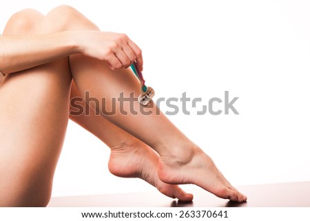 The girl is holding a razor in his hand and shave her legs.