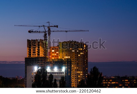 High buildings under construction with cranes and illumination at night