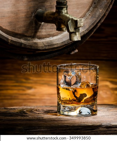 glass of whiskey or brandy ice poured from an old oak barrel