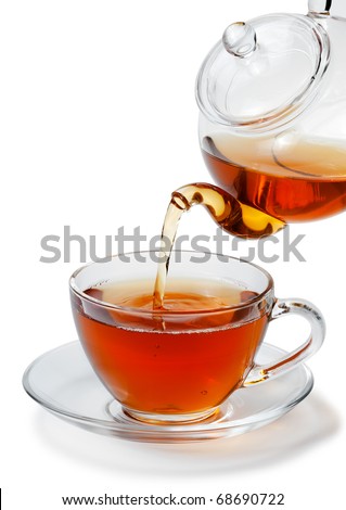 Tea being poured into glass tea cup isolated on a white background.