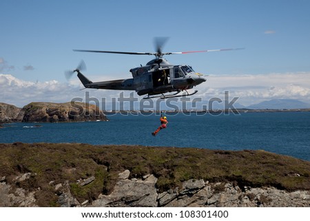 Search and Rescue Training  with a winchman hanging on the end of a wire RAF Valley Anglesey UK