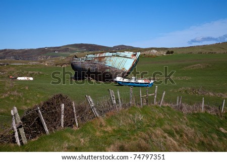Old boat beached on a field on the coastal path Isle Anglesey North wales