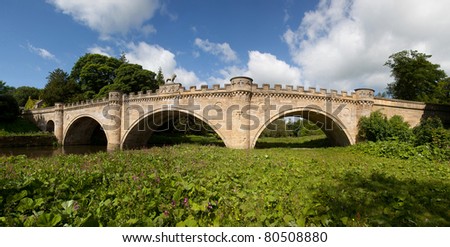 Alnwick Castle on the River Aln with the Lion bridge spanning it Northumberland England Uk