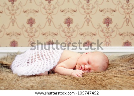 Newborn baby boy asleep on a fur blanket. Soft focus.
