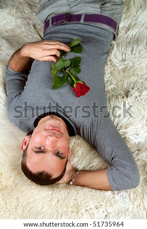 A sexy young man with rose lying on the floor