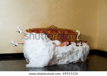 Caucasian bride relaxing on love seat.