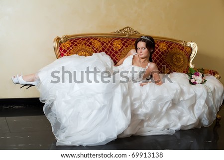 Caucasian bride relaxing on love seat.