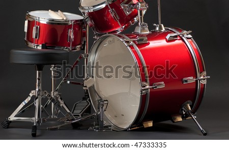 A bottom half shot of a junior-size drum kit, emphasizing the snare and bass drums, isolated in a dark background.