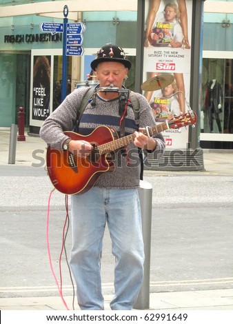 MANCHESTER, ENGLAND - SEPTEMBER 25: One Man Band Busker entertaining shoppers on September 25, 2010 in Manchester, England. Buskers in Manchester are becoming much more common recently.