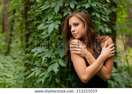 Young beautiful woman in black dress in the forest