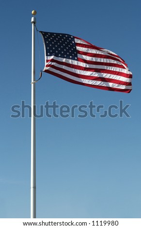 American flag flying in the wind against a blue sky.