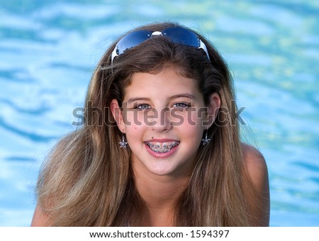 Pretty teenage girl in a pool wearing sunglasses on top of her head.