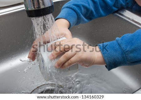 Boy doing the dishes in the sink
