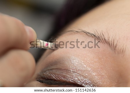 Beautician tweezing woman eyebrows in a spa center