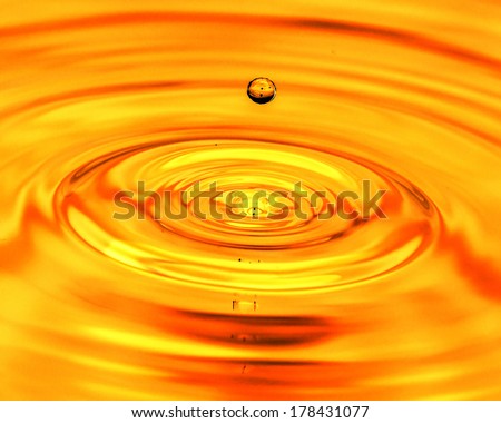 a drop of water falls in a golden water. macro