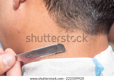 Hairdresser shaving man\'s neck with a straight razor
