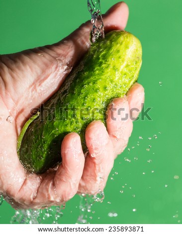 cucumber in his hand in the water on a green background
