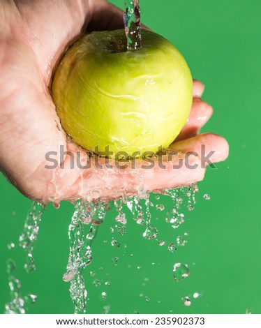 apple in his hand in the water on a green background