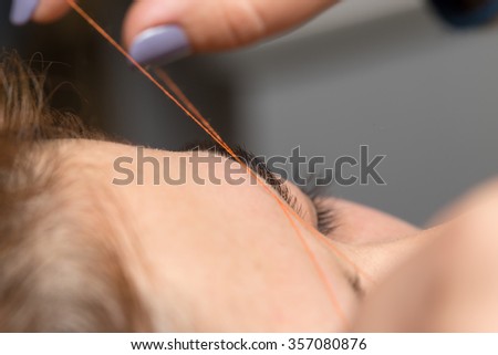 Grooming the eyebrows thread in a beauty salon. close