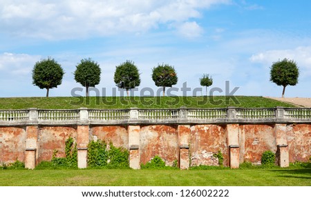 Mason wall and row of trees on the grounds of Peterhof Palace in Saint Petersburg, Russia