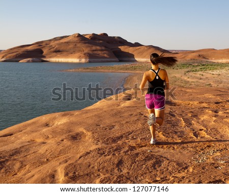 Young woman having a morning work out and run along the shore of Lake Powell in the southwestern US desert.