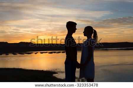 Loving young couple enjoying a summer sunset together at the lake.