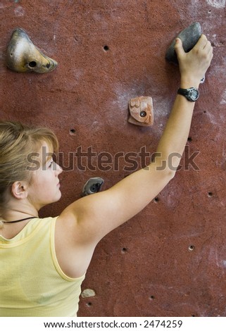 Pretty, young, athletic girl climbing on an indoor rock-climbing wall