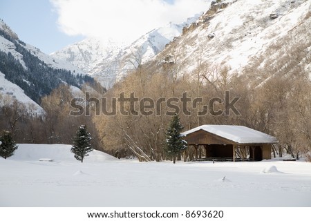 A snow-covered picnic pavilion in the mountains of Utah in the winter with mountains in the background