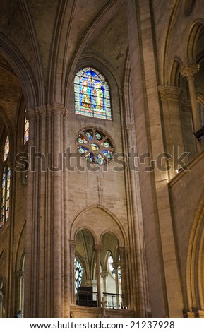 An interior wall inside Notre Dame Cathedral that includes a stained glass windowand ceiling