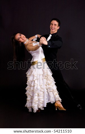 Young ballroom dancers in formal costumes posing against a solid background in a studio
