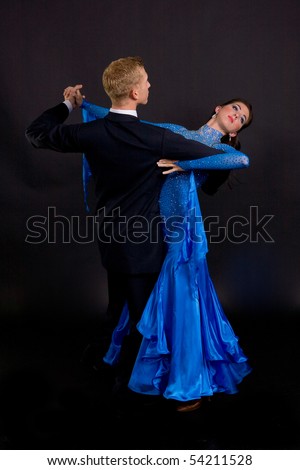 Young ballroom dancers in formal costumes posing against a solid background in a studio