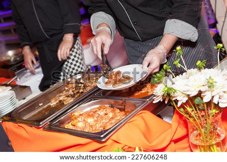 Hands of cook serving food at a catered event