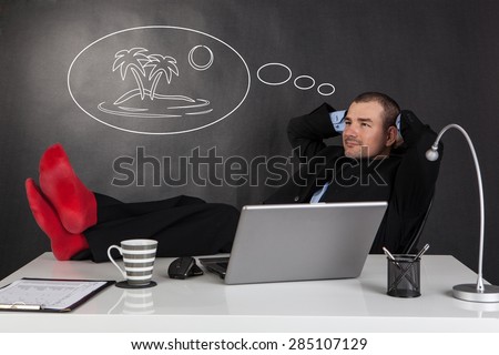 Businessman relaxing with feet over up his desk and dreaming about his vacation