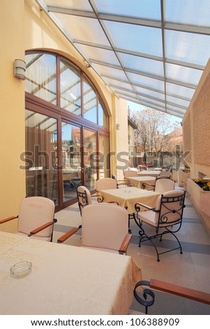 Interior of a restaurant balcony, spring time, just tables and chairs, during day.