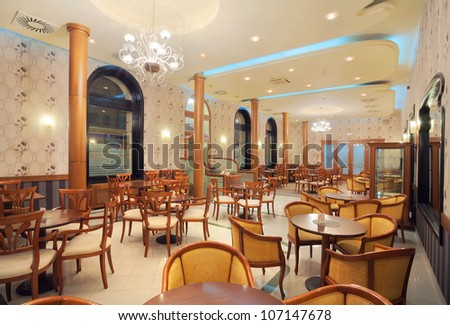 Interior of a restaurant, vintage style, wooden classical furniture, retro wallpapers, during night.