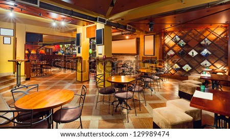 Interior of a modern pub in orange and wooden colors.