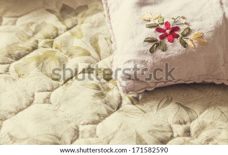 Details of a pillow on bed sheet, closeup of embroidery work.