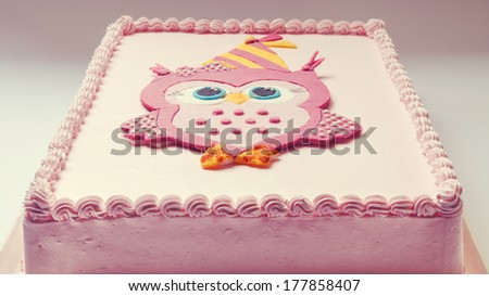 Pink birthday cake with funny owl on top.