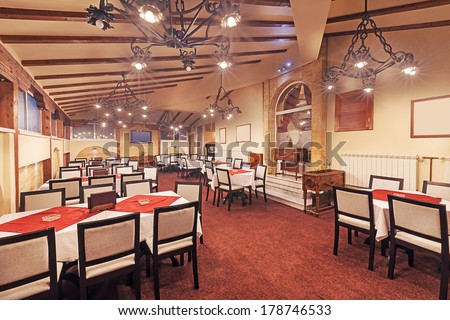 Interior of a modern restaurant. Empty room with furniture and old metal chandeliers, vintage design mixed with contemporary.