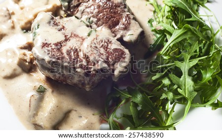Steak in cream and mushrooms, served on white plate.