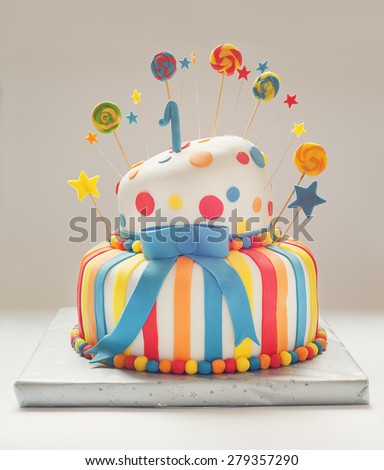 Funny birthday cake with number one on top, sweet colorful decoration.