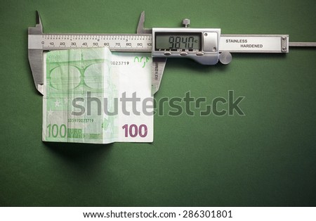 Conceptual composition representing money devaluation, symbolically showed with sliding caliper measuring a hundred euros.