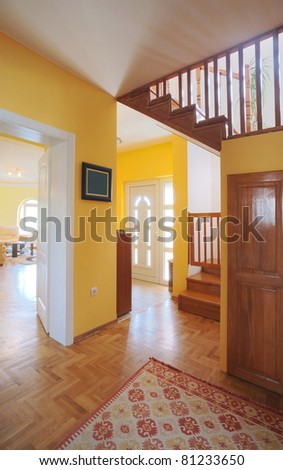 Entrance hall of a modern house, view on rooms and wooden stairs.