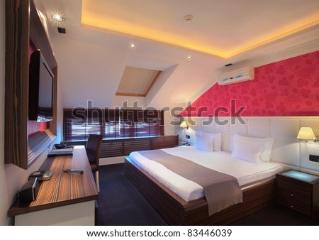 Interior of a hotel room for two, double bed and red wallpapers.